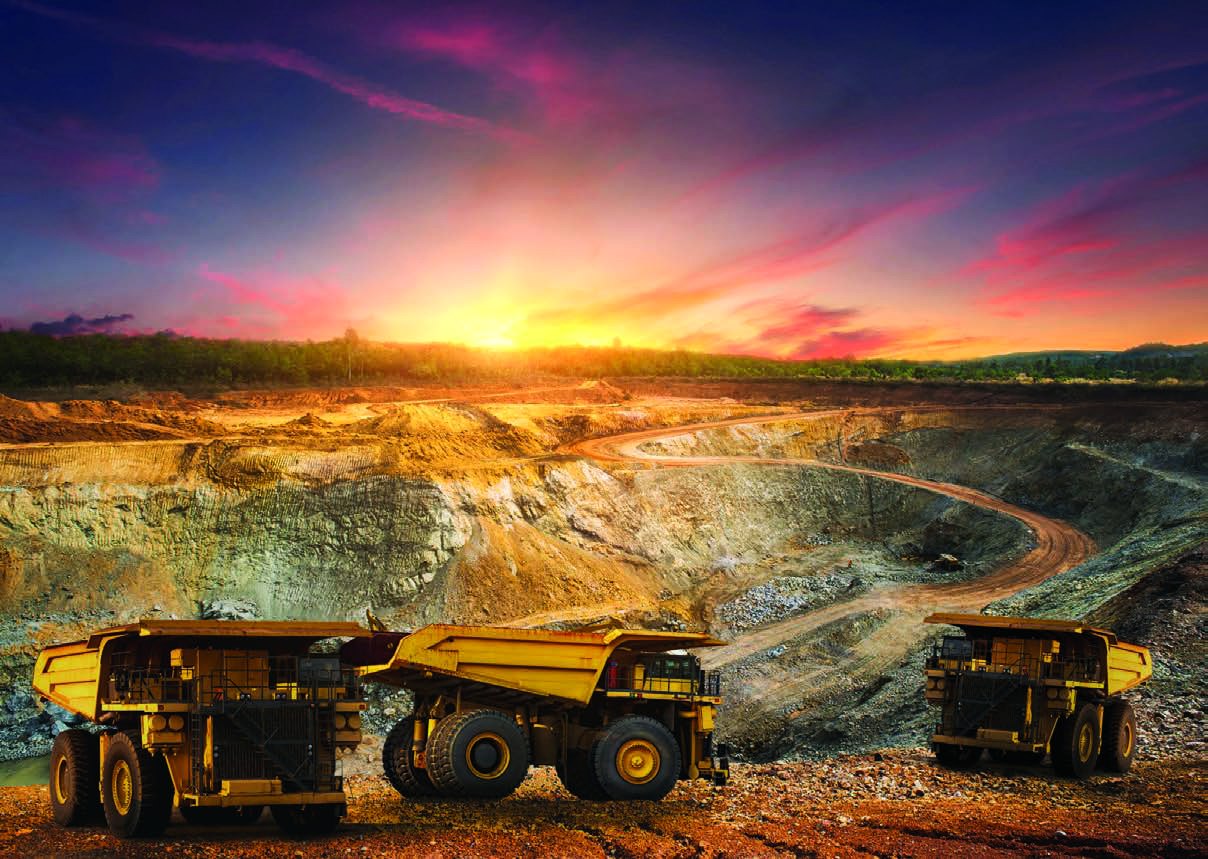 Open-pit mining landscape with haul trucks at sunset, illustrative photograph featured in the company handbook